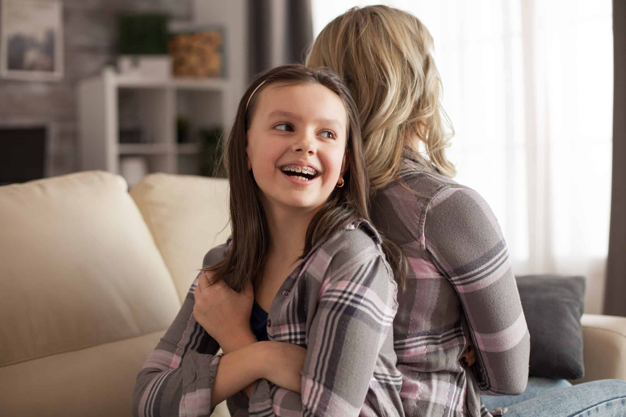 Girl with braces back to back with mother